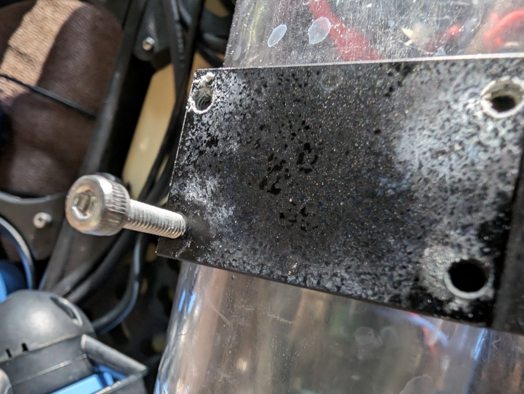 Powdery residue, aluminum oxide, from galvanic corrosion between the stainless steel bolt and the aluminum watertight enclosure clamp